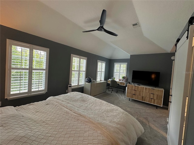 bedroom with vaulted ceiling, multiple windows, carpet floors, and a barn door