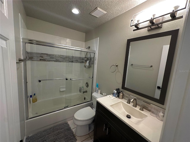 full bathroom with tile patterned flooring, a textured ceiling, shower / bath combination with glass door, vanity, and toilet