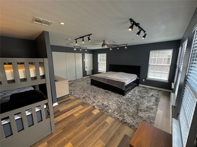 bedroom with multiple windows, hardwood / wood-style floors, and a textured ceiling