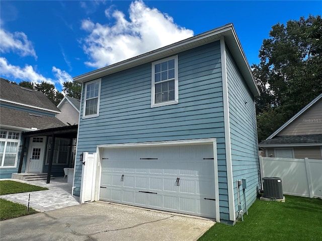 view of front of house featuring a garage, central air condition unit, and a front yard