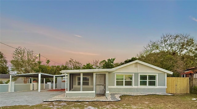 back house at dusk with a yard, a sunroom, and a carport