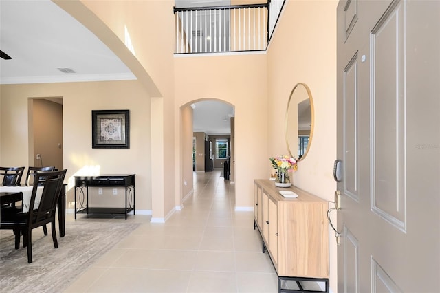 entrance foyer with a high ceiling, light tile patterned floors, and crown molding