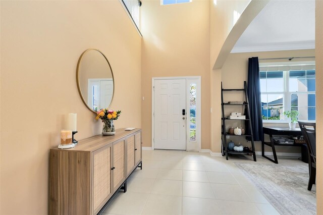 foyer with a wealth of natural light, ornamental molding, and a towering ceiling