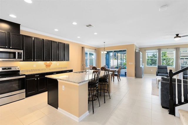 kitchen with appliances with stainless steel finishes, decorative light fixtures, sink, an island with sink, and a kitchen breakfast bar