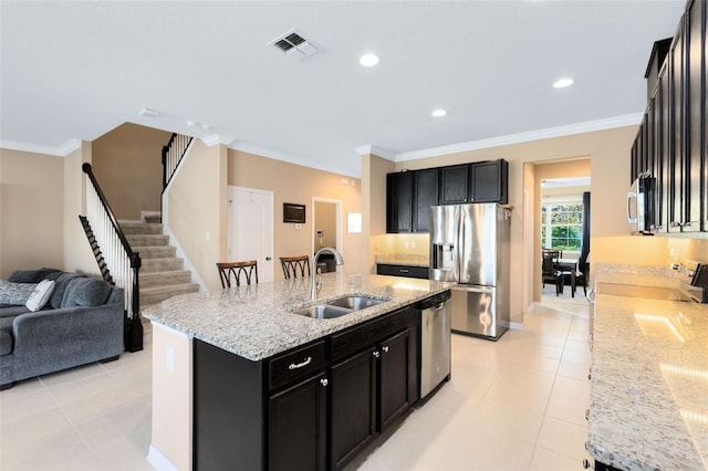 kitchen featuring stainless steel appliances, sink, an island with sink, ornamental molding, and light stone countertops