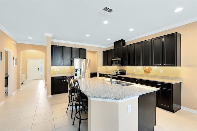 kitchen featuring stainless steel appliances, sink, an island with sink, ornamental molding, and a breakfast bar