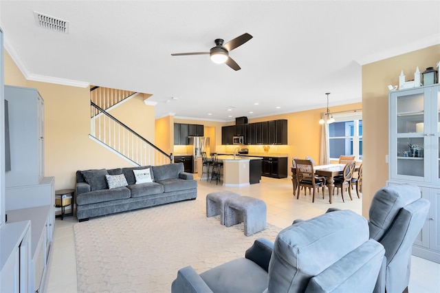 tiled living room featuring ornamental molding and ceiling fan with notable chandelier