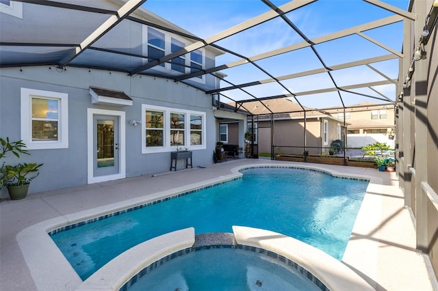 view of swimming pool with glass enclosure, a patio, and an in ground hot tub