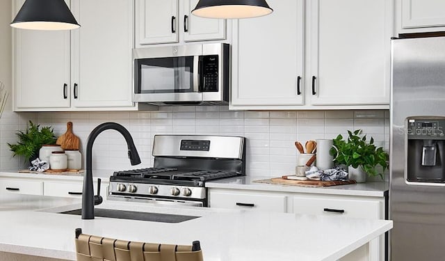 kitchen with white cabinets, hanging light fixtures, appliances with stainless steel finishes, and backsplash