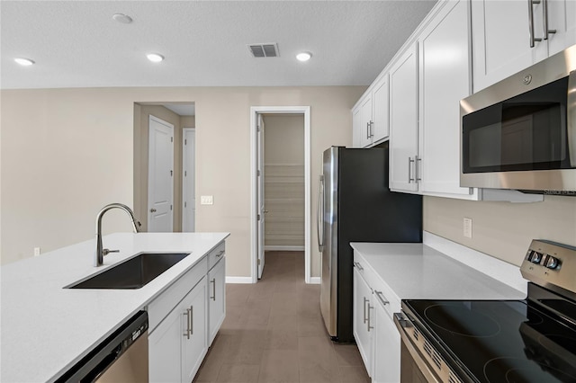 kitchen with stainless steel appliances, sink, white cabinets, and a textured ceiling