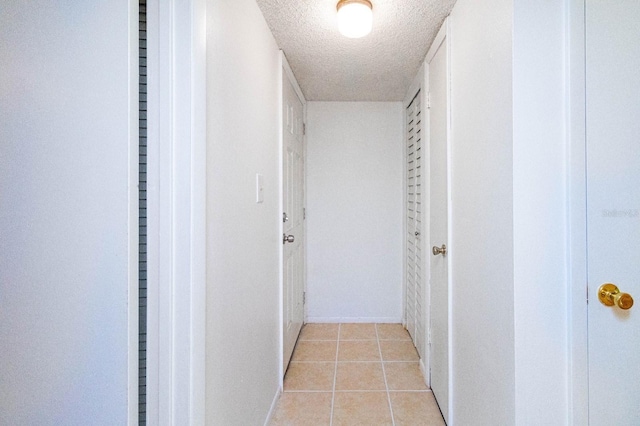 hall with a textured ceiling and light tile patterned flooring