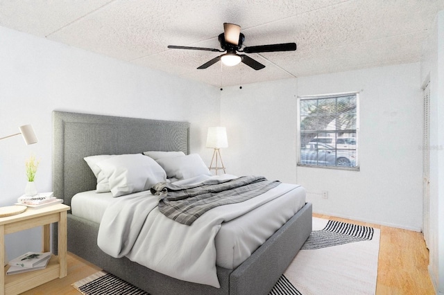 bedroom featuring ceiling fan, a textured ceiling, and light wood-type flooring