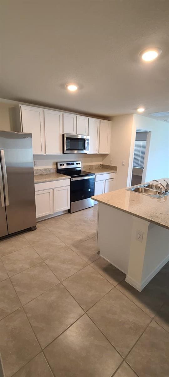 kitchen featuring appliances with stainless steel finishes, light stone countertops, sink, and white cabinets