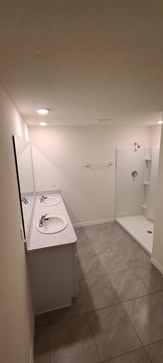 bathroom with a shower, tile patterned flooring, and vanity