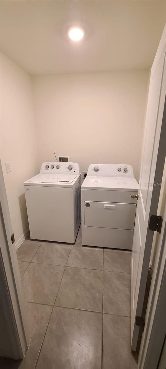 washroom with independent washer and dryer and light tile patterned flooring