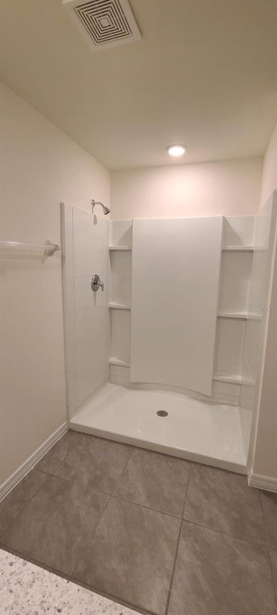 bathroom with a shower and tile patterned flooring