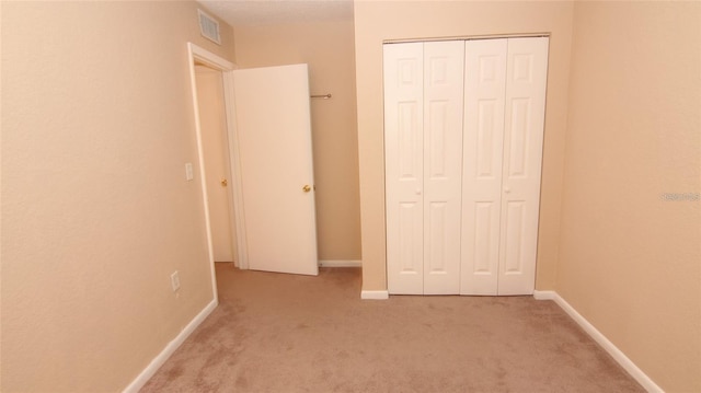 unfurnished bedroom featuring a closet and light colored carpet