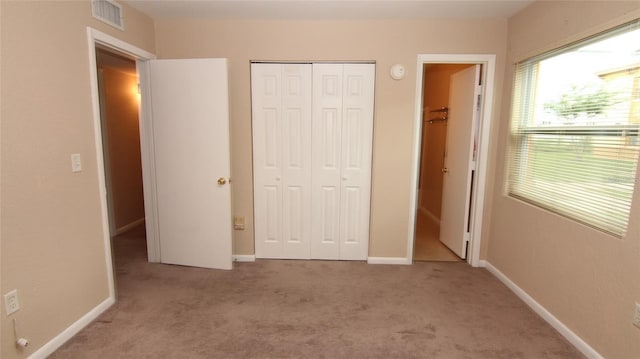 unfurnished bedroom featuring a closet and light carpet