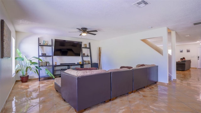 tiled living room with a wealth of natural light, ceiling fan, and a textured ceiling