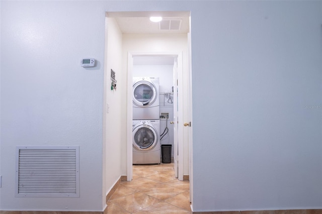 laundry room with stacked washer and clothes dryer and light tile patterned floors