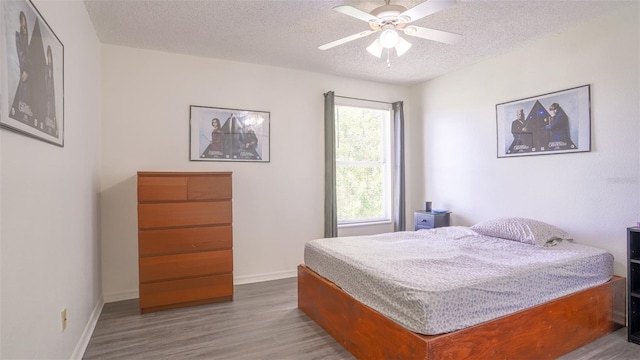 bedroom featuring ceiling fan, hardwood / wood-style floors, and a textured ceiling