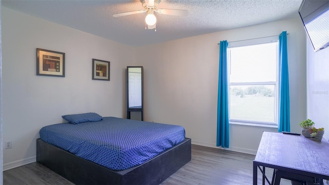 bedroom with ceiling fan, hardwood / wood-style floors, and a textured ceiling