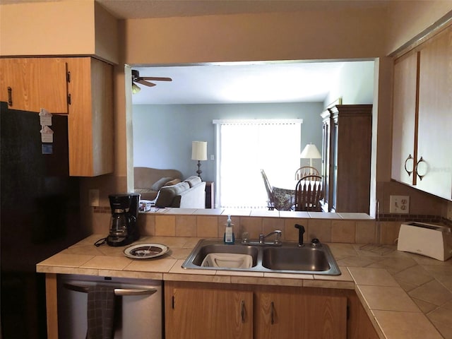 kitchen with black fridge, sink, stainless steel dishwasher, and tile counters