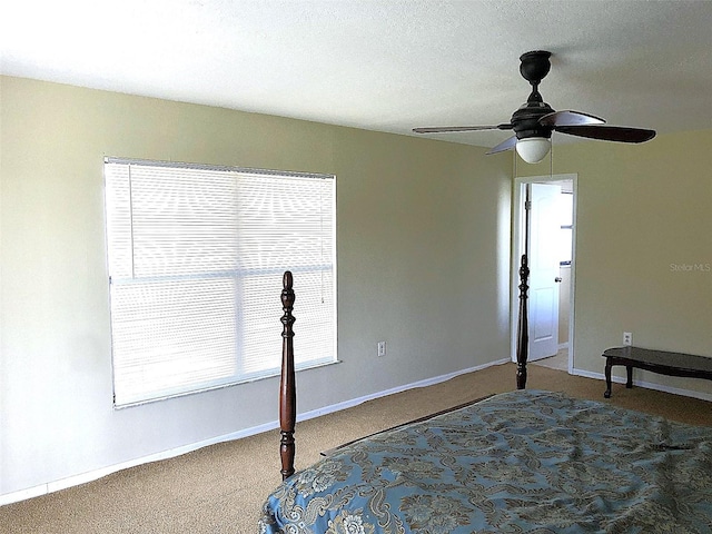 carpeted bedroom featuring ceiling fan and a textured ceiling