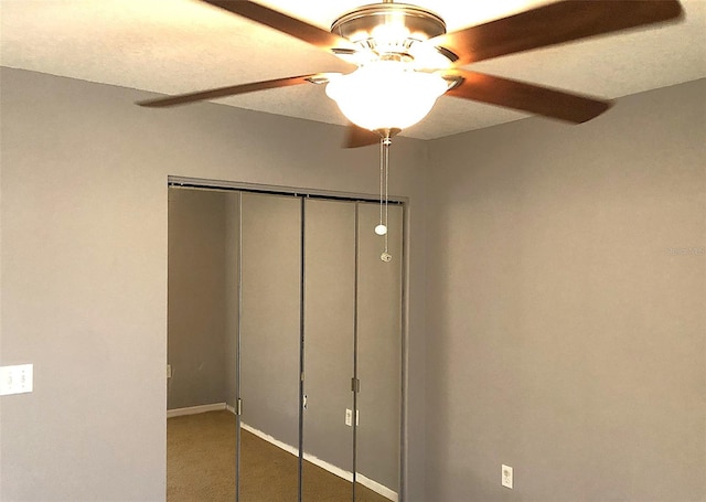 unfurnished bedroom with a closet, ceiling fan, and dark carpet