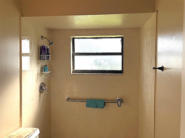 bathroom featuring toilet and tiled shower