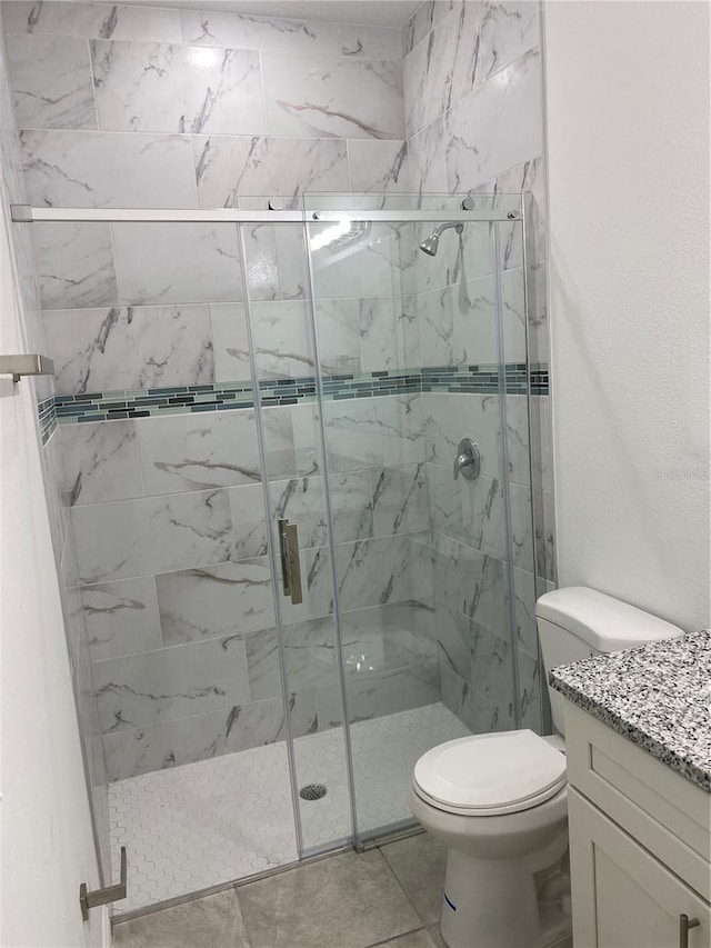 bathroom featuring toilet, an enclosed shower, tile patterned floors, and vanity