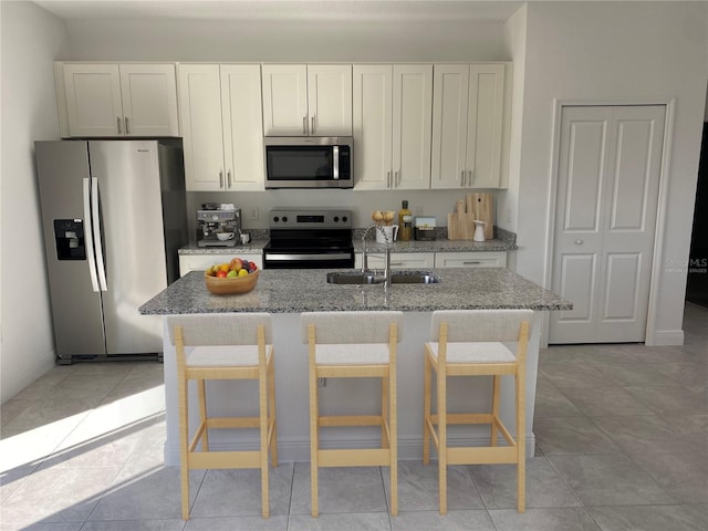 kitchen with sink, light stone counters, a kitchen bar, and appliances with stainless steel finishes