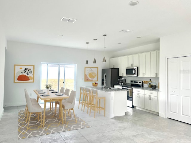 kitchen featuring decorative light fixtures, white cabinetry, stone countertops, and stainless steel appliances