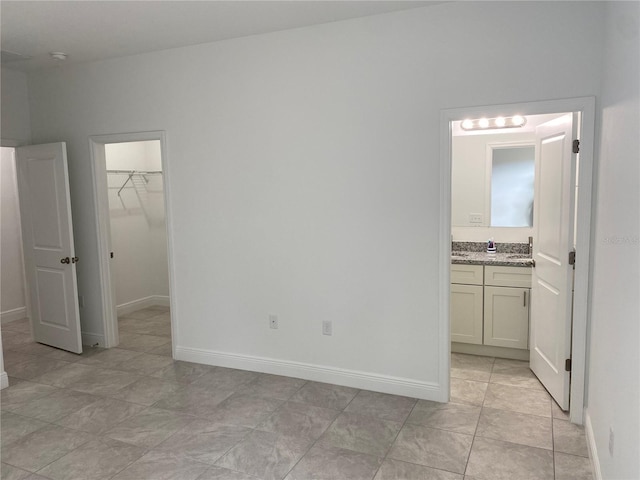 unfurnished bedroom with a closet, connected bathroom, a spacious closet, and sink