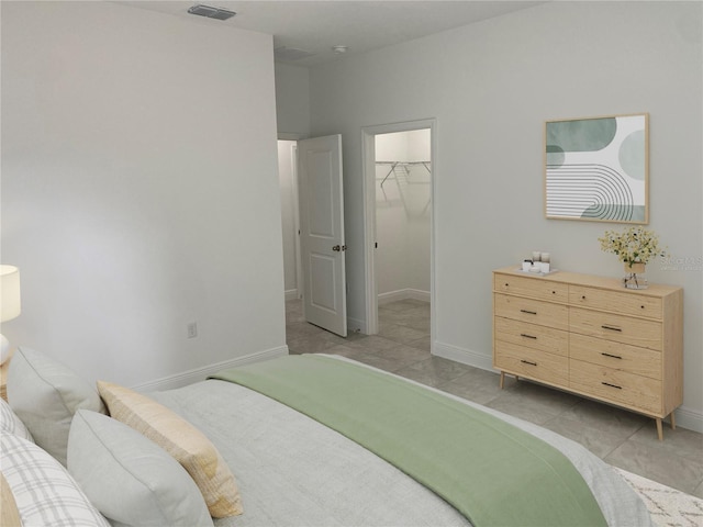 bedroom with a closet, light tile patterned floors, and a walk in closet