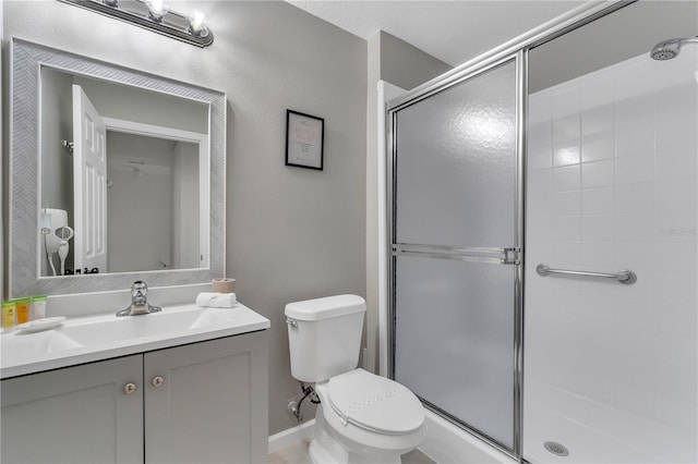 bathroom with vanity, toilet, and a shower with door