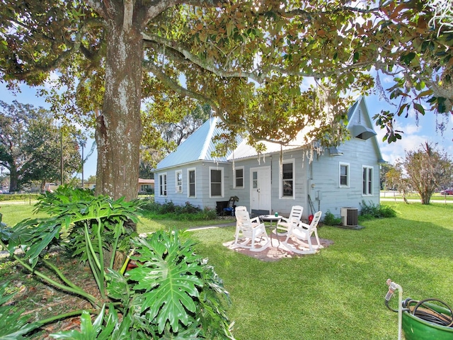 back of property with central air condition unit, a patio, and a lawn