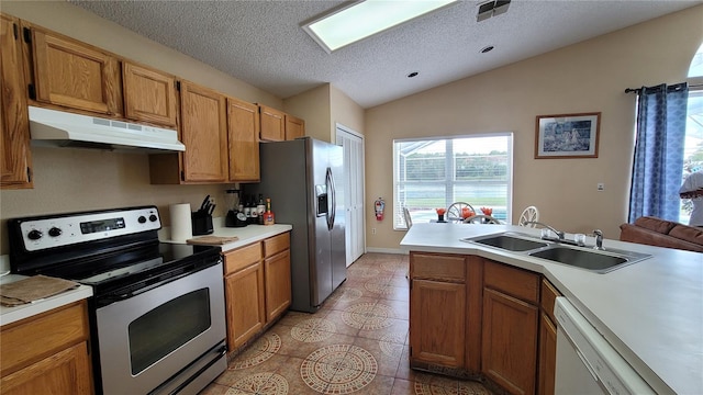 kitchen featuring a textured ceiling, sink, lofted ceiling, stainless steel appliances, and light tile patterned floors