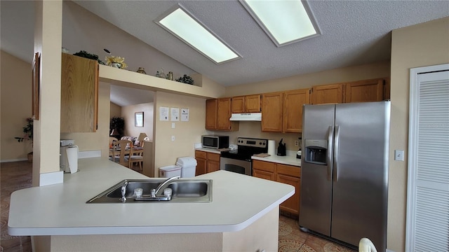 kitchen featuring a textured ceiling, sink, vaulted ceiling, kitchen peninsula, and appliances with stainless steel finishes