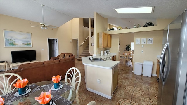 kitchen with sink, kitchen peninsula, ceiling fan, light brown cabinetry, and stainless steel fridge