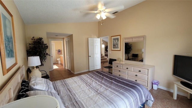 tiled bedroom featuring ceiling fan, a textured ceiling, lofted ceiling, and ensuite bath