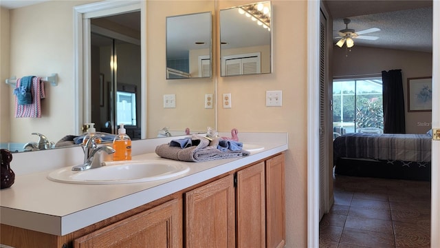 bathroom with vaulted ceiling, vanity, a textured ceiling, ceiling fan, and tile patterned floors