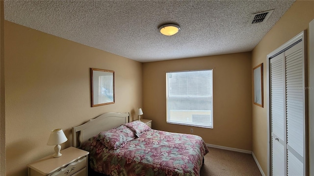 carpeted bedroom featuring a textured ceiling and a closet