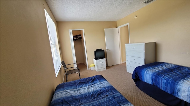 carpeted bedroom featuring a textured ceiling, a spacious closet, and a closet