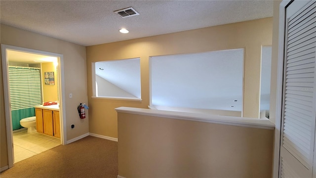 hall featuring a textured ceiling and light colored carpet