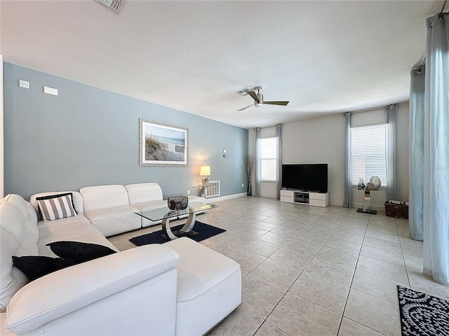 living room featuring ceiling fan, light tile patterned floors, and a textured ceiling