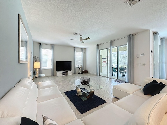 tiled living room with ceiling fan and a textured ceiling