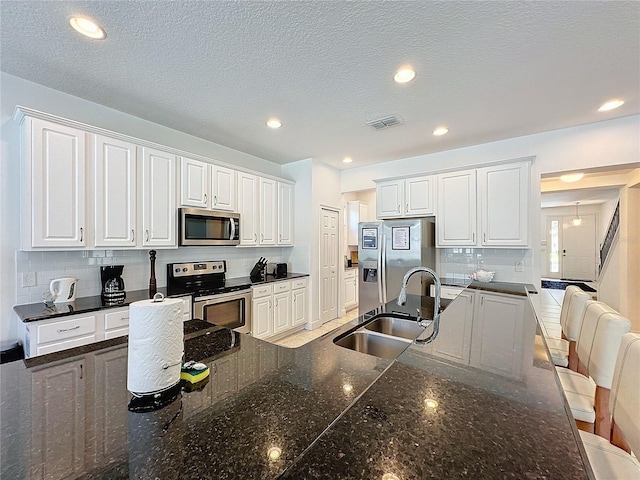 kitchen featuring appliances with stainless steel finishes, tasteful backsplash, a kitchen breakfast bar, sink, and white cabinetry