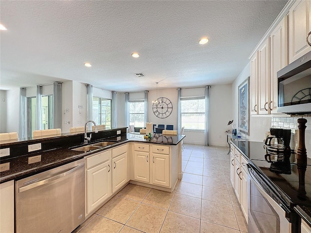 kitchen featuring sink, kitchen peninsula, white cabinetry, and stainless steel appliances