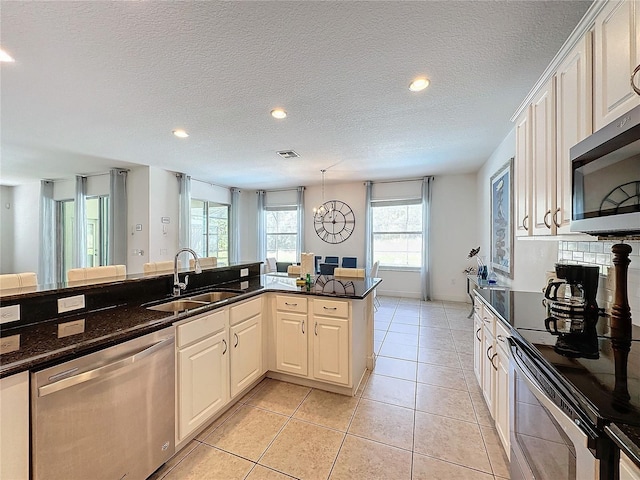 416 Orange Cosmos Blvd, Davenport, FL 33837 - kitchen featuring stainless steel appliances, a sink, light tile patterned flooring, dark stone countertops, and a textured ceiling